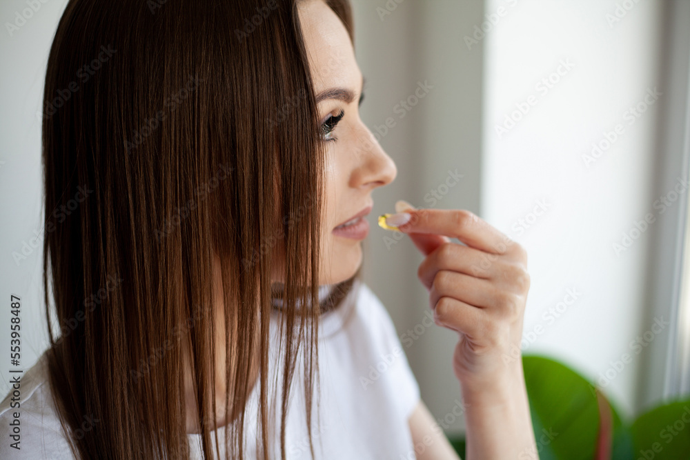 Closeup Of Beautiful Young Woman Taking Yellow Fish Oil Pill. Closeup Of Beautiful Young Woman Taking Yellow Fish Oil Pill.