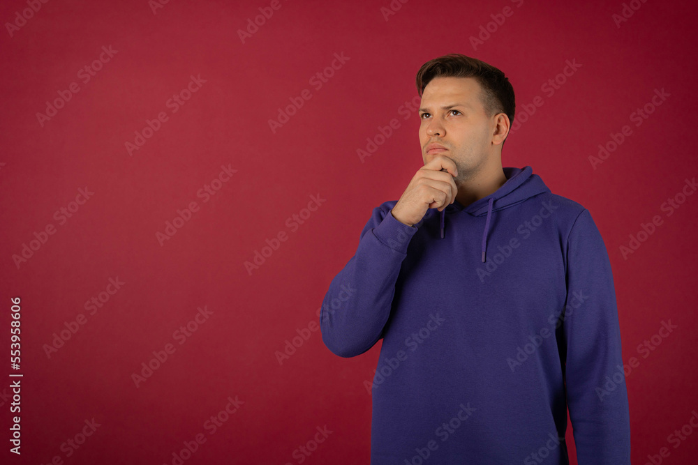 Attractive young man in a purple sweatshirt on a red background Attractive young man in a purple sweatshirt on a red background