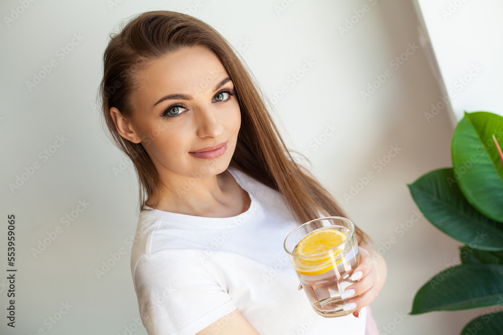 Beautiful youthful lady refreshing herself with lemon water