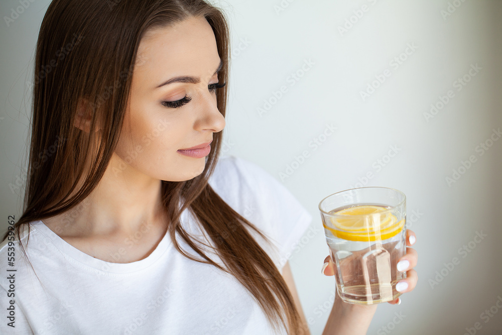 Beautiful youthful lady refreshing herself with lemon water Beautiful youthful lady refreshing herself with lemon water