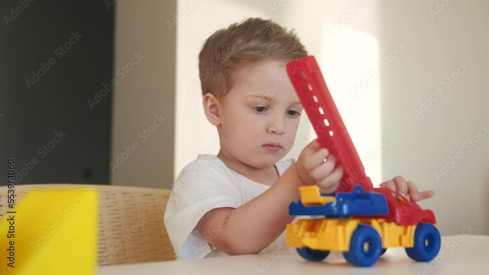 boy kid playing toy in kindergarten. indoors happy family kid dream education concept. baby son plays toys colored cubes on the table in kindergarten. blond boy 2 years playing toys boy kid playing toy in kindergarten. indoors happy family kid dream education concept. baby son plays toys colored cubes on the table in kindergarten. blond boy 2 years playing toys