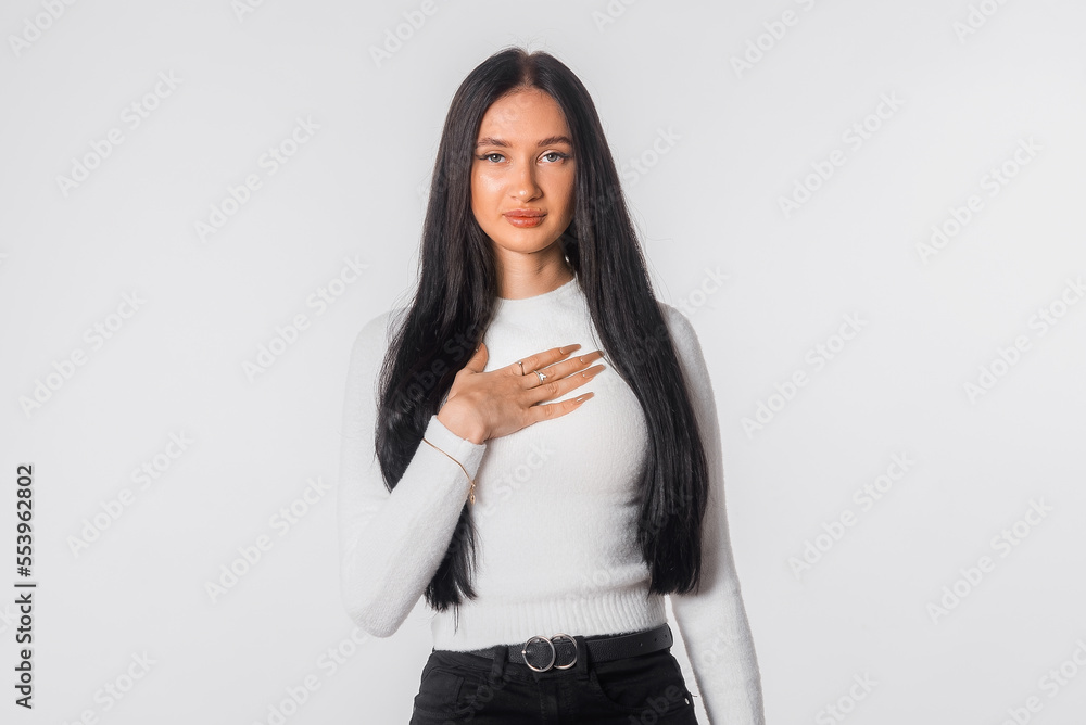 Young woman looks embarrassed, feels confused. Shy girl stands against white background. Lack of confidence. Human emotion body language life perception Young woman looks embarrassed, feels confused. Shy girl stands against white background. Lack of confidence. Human emotion body language life perception
