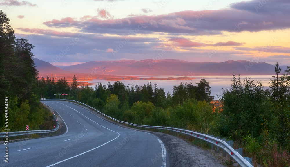 beautiful road beyond the Arctic Circle at sunset with a view of the northern sea, forest and mountains. Landscapes of the Kola Peninsula in the Murmansk region of Russia near the city of Kandalaksha