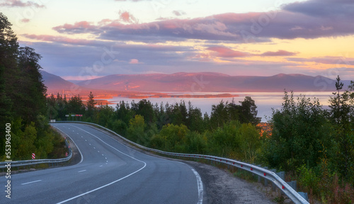 beautiful road beyond the Arctic Circle at sunset with a view of the northern sea, forest and mountains. Landscapes of the Kola Peninsula in the Murmansk region of Russia near the city of Kandalaksha photo