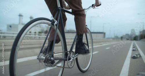 Side shot of young man ride bike on way to work in urban industrial area of city. Fast and confident cyclist ride commuter bicycle to school. Commuting as new way to travel and move around