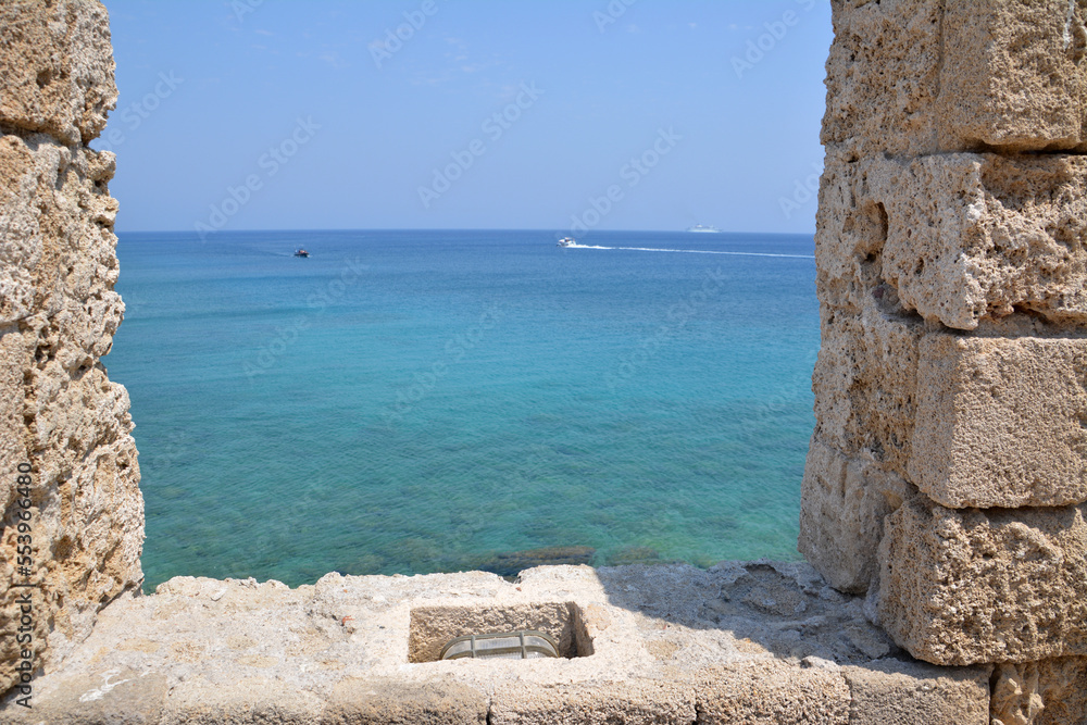 turquoise water of mediterranean sea with blue sky on horizon through brick window
