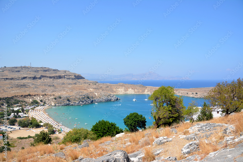 bay of water surrounded with hills and clear blue sky on background, Greece Lindos
