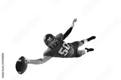 Monochrome portrait of professional american football player in sports uniform and protective helmet in motion isolated over white background.