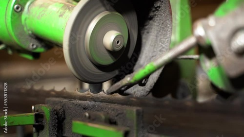Automatic band saw blade sharpening with industrial machinery in closeup photo