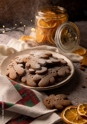 Christmas gingerbread cookies sprinkled with powdered sugar with dried oranges laying around