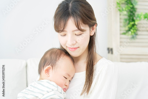 家で眠る赤ちゃんを抱っこする母親