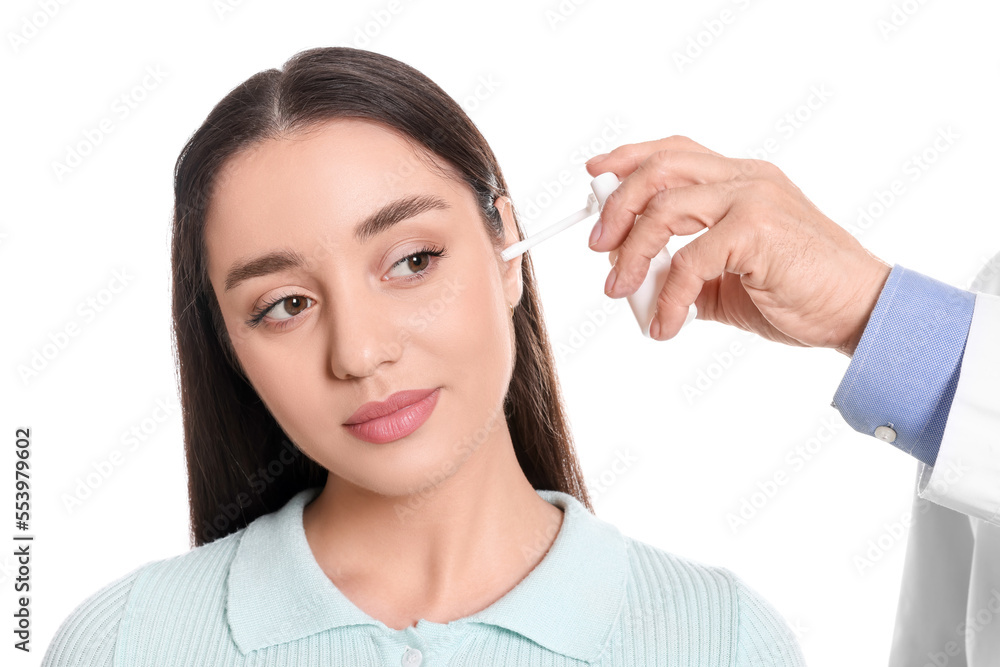 Doctor spraying medication into woman's ear on white background Doctor spraying medication into woman's ear on white background