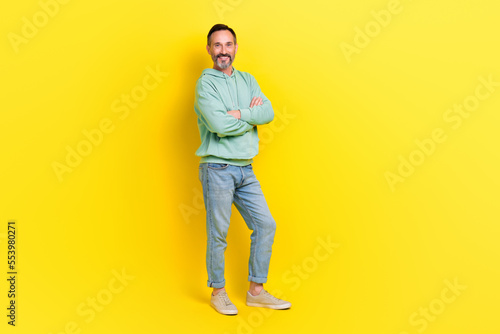 Full length photo of good looking man wear fashionable clothes arm crossed stand empty space ad banner isolated on yellow color background