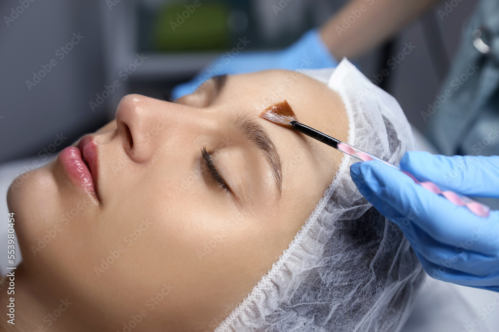 Cosmetologist applying chemical peel product on client's face in salon, closeup Cosmetologist applying chemical peel product on client's face in salon, closeup