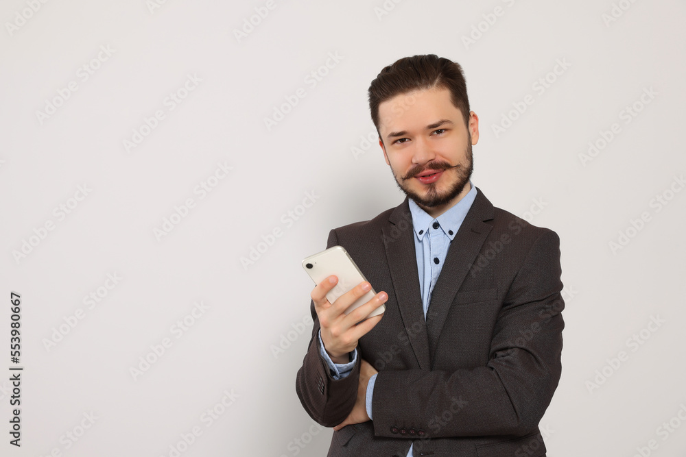 Smiling man in suit with smartphone against light grey background. Space for text Smiling man in suit with smartphone against light grey background. Space for text