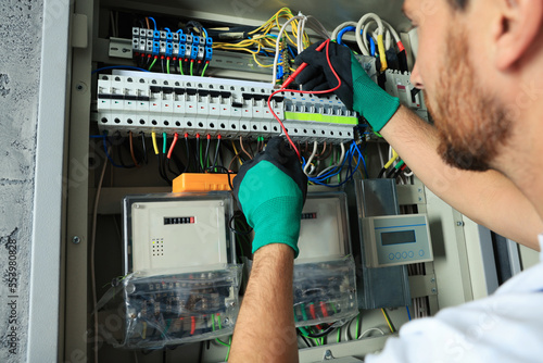 Electrician checking electric current with multimeter indoors, closeup