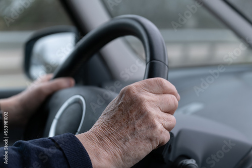 Une personne agée qui conduit une voirure les mains sur le volant photo