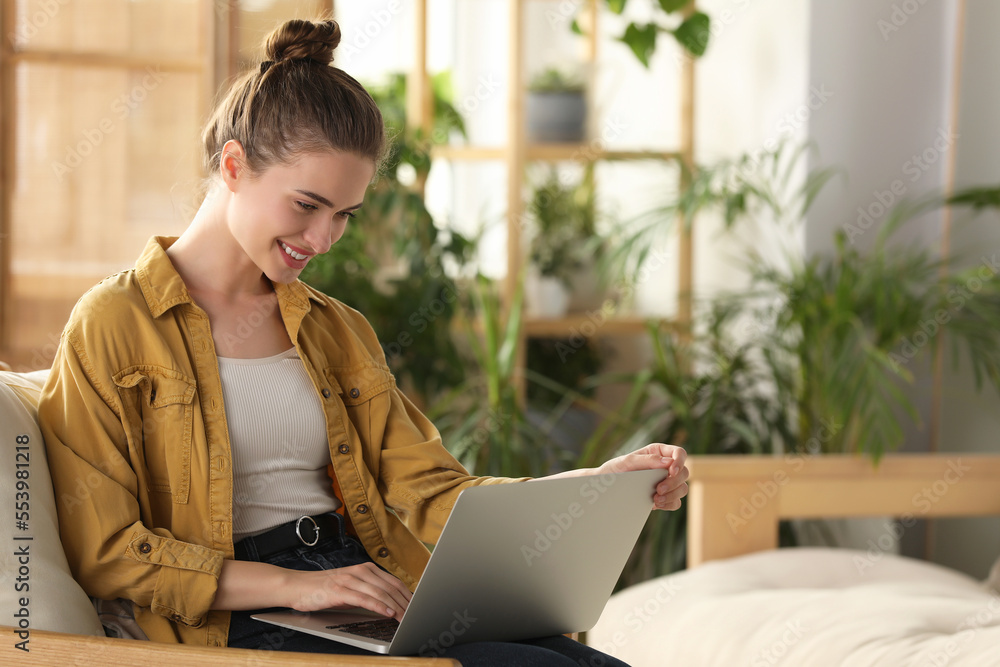 Happy young woman with laptop on armchair at home Happy young woman with laptop on armchair at home