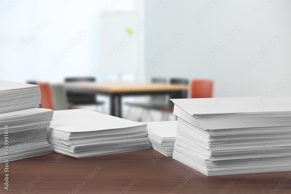 Stacked sheets of paper on wooden table in office, space for text Stacked sheets of paper on wooden table in office, space for text