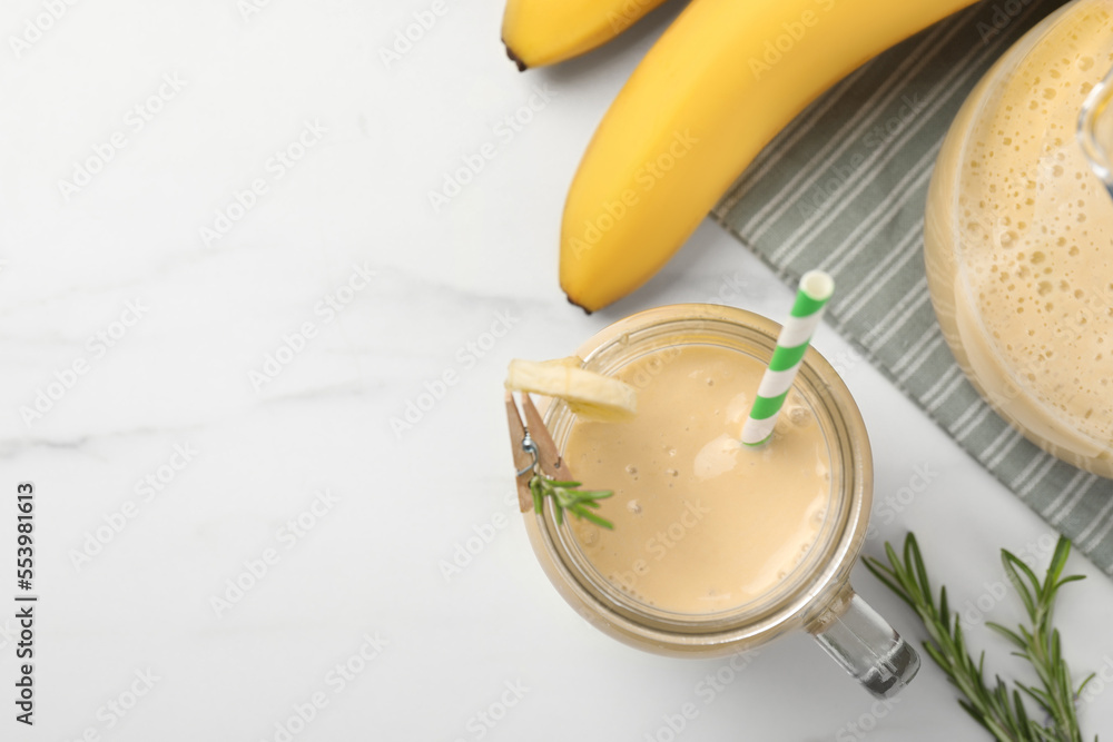 Mason jar of tasty banana smoothie with straw and fresh fruits on white marble table, flat lay. Space for text Mason jar of tasty banana smoothie with straw and fresh fruits on white marble table, flat lay. Space for text