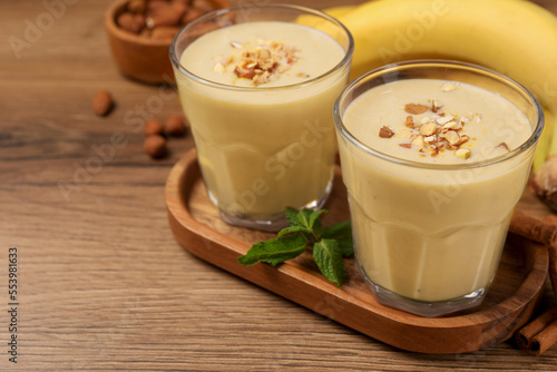 Tasty banana smoothie with almond and cinnamon on wooden table. Space for text