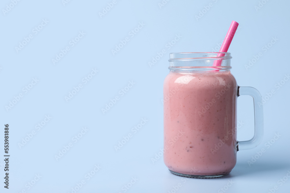 Mason jar with delicious berry smoothie on light blue background. Space for text Mason jar with delicious berry smoothie on light blue background. Space for text
