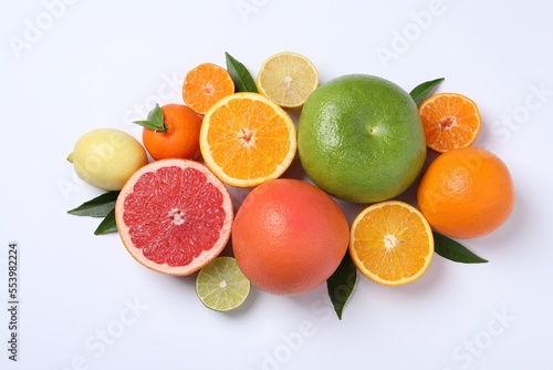 Different citrus fruits with fresh leaves on white background  top view