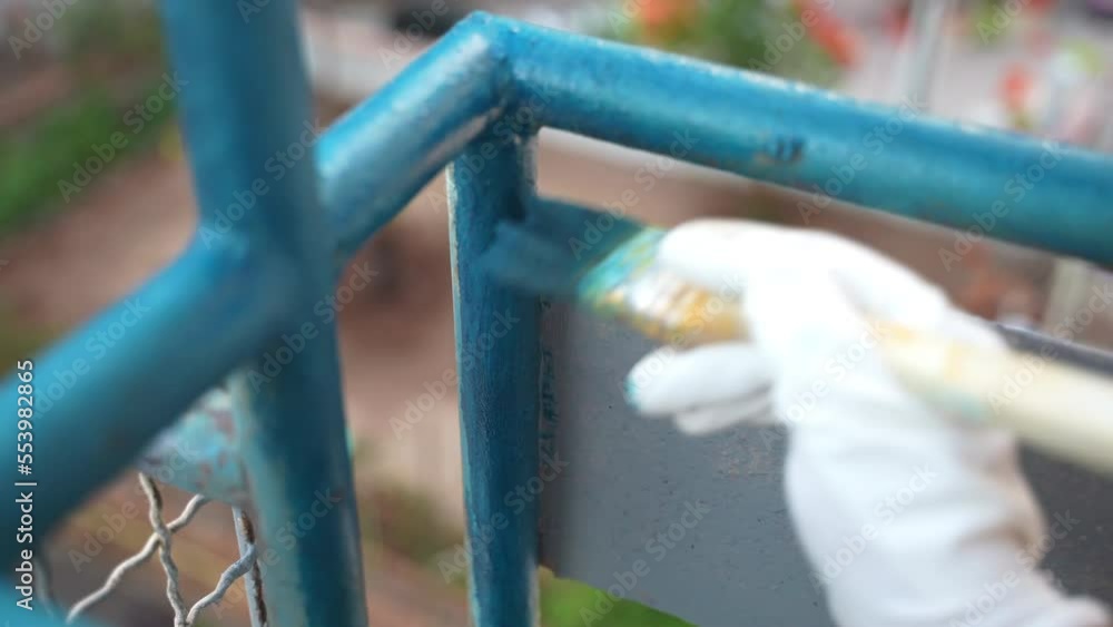 Worker using soft paintbrush for painting balcony iron frames with blue colour, repairman reconstructing old metal surface with modern efficient chemical solution, renewal of steel surface with Worker using soft paintbrush for painting balcony iron frames with blue colour, repairman reconstructing old metal surface with modern efficient chemical solution, renewal of steel surface with