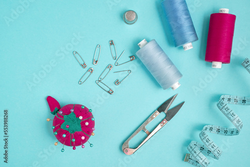 Sewing accessories on a blue background. Measuring tape, pins, scissors and thread.