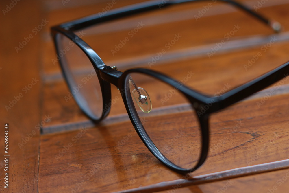 a close up of eyeglasses with black frames isolated natural patterned wooden background. a close up of eyeglasses with black frames isolated natural patterned wooden background.