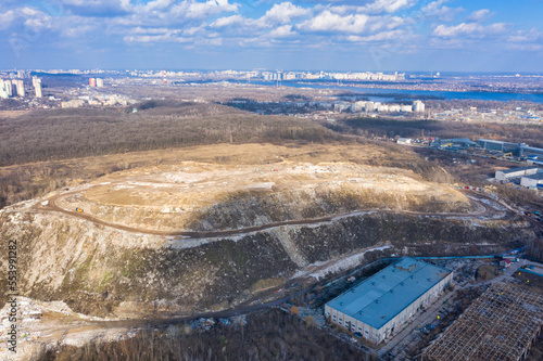 Huge household waste dump next to a three-story building: huge mountains of garbage - damage to the environment. The problem of garbage disposal in cities. photo