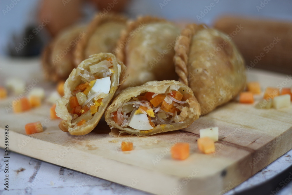 a close up of pastel cake which is a traditional indonesian food. filled with chicken, vegetables, or boiled eggs and served with sauce or chili. Indonesian traditional food photo concept.
