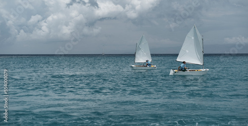 Greek Islands, Greece : 29 May 2022 : optimist sailing team on training in the sea close to coast , sailing sport activity, teenager outdoors