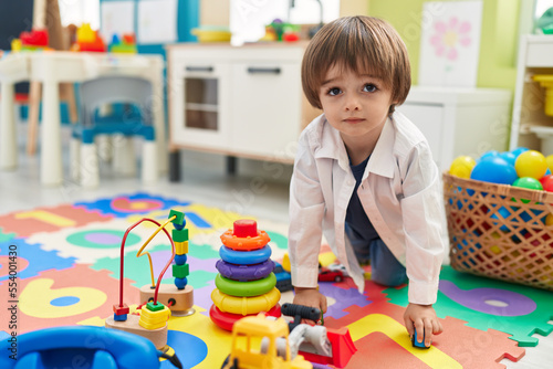 Adorable toddler playing with truck toy sitting on floor at kindergarten