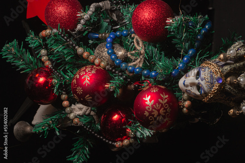 Red Christmas ball on a Christmas tree with a garland on the black background