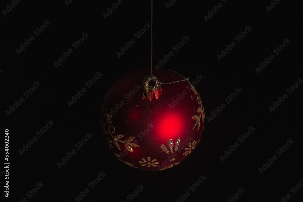 Red Christmas ball on a Christmas tree with a garland on the black background Red Christmas ball on a Christmas tree with a garland on the black background