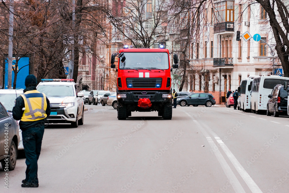 Fototapeta premium Modern fire-fighting truck moving toward the city's road. City. Emergency. Engine. Fire. Service. Shiny. Urgency. Alarm. Department. Firetruck. Health. Siren