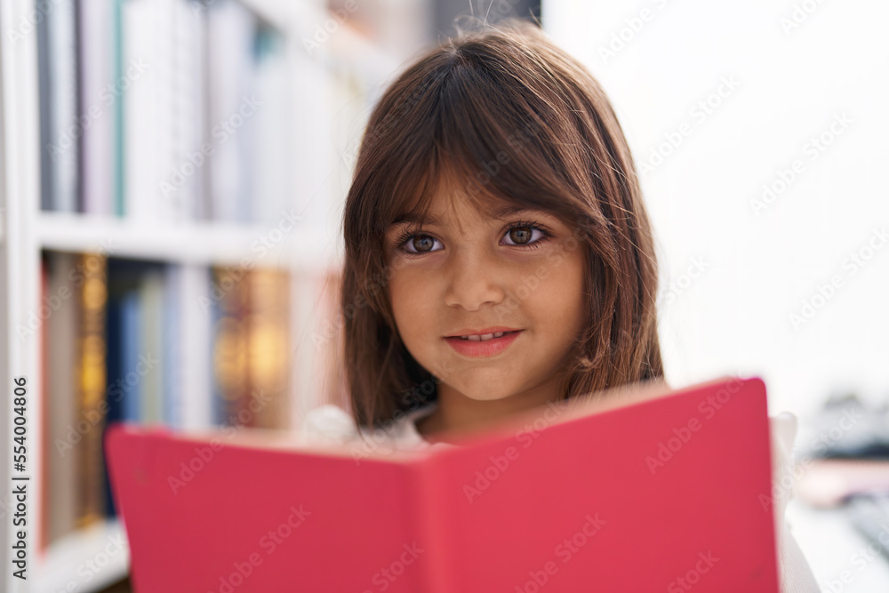 Adorable hispanic girl student smiling confident reading book at classroom Adorable hispanic girl student smiling confident reading book at classroom