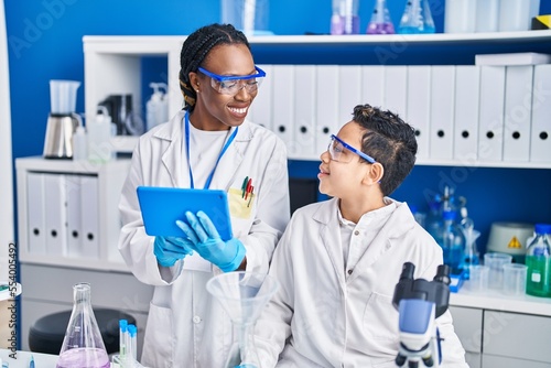 African american mother and son scientists using touchpad working laboratory