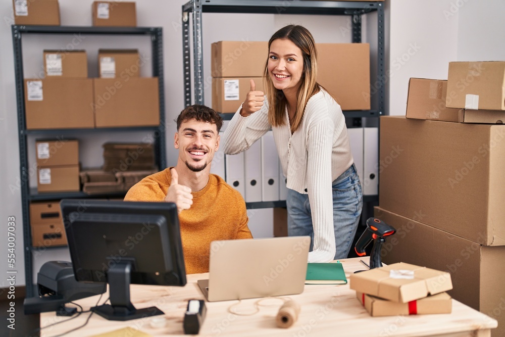 Young couple working at small business ecommerce smiling happy and positive, thumb up doing excellent and approval sign Young couple working at small business ecommerce smiling happy and positive, thumb up doing excellent and approval sign