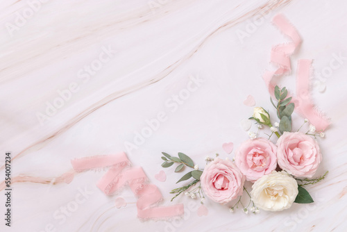 Fototapeta Naklejka Na Ścianę i Meble -  Pink and cream roses and silk ribbons on white marble top view, Romantic wedding background