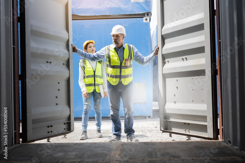 The man and woman are opening the doors of a cargo container.