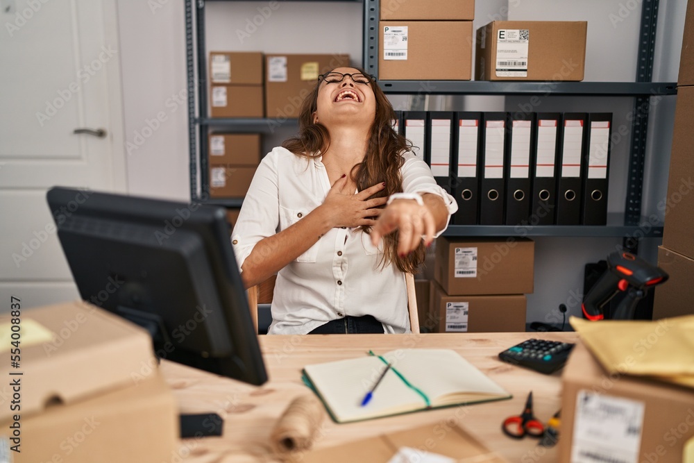 Young hispanic woman working at small business ecommerce laughing at you, pointing finger to the camera with hand over body, shame expression Young hispanic woman working at small business ecommerce laughing at you, pointing finger to the camera with hand over body, shame expression