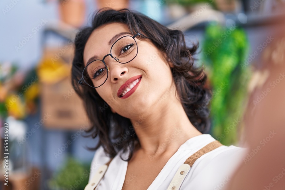 Young beautiful hispanic woman florist smiling confident make selfie by camera at flower shop