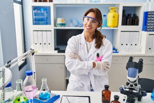 Young latin woman wearing scientist uniform standing with arms crossed gesture at laboratory