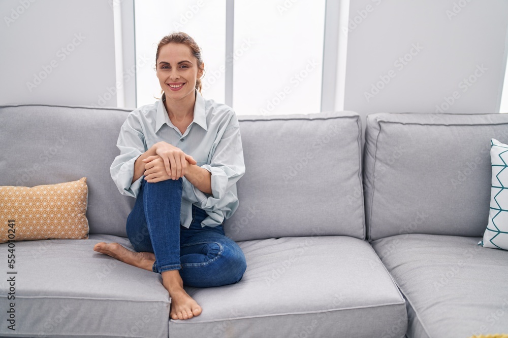 Young woman smiling confident sitting on sofa at home Young woman smiling confident sitting on sofa at home