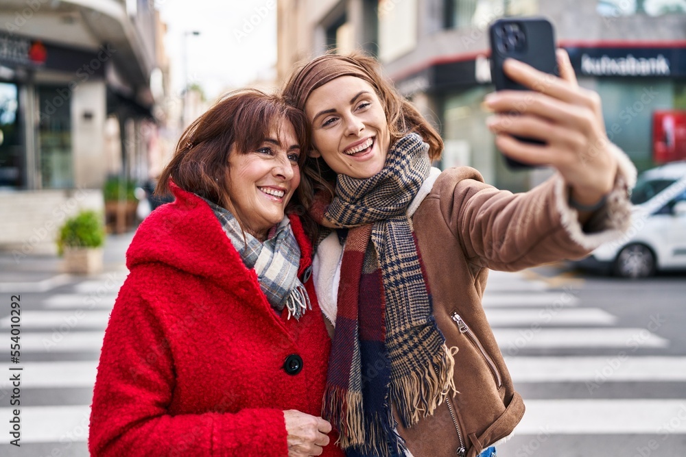 Two women mother and daughter make selfie by smartphone at street