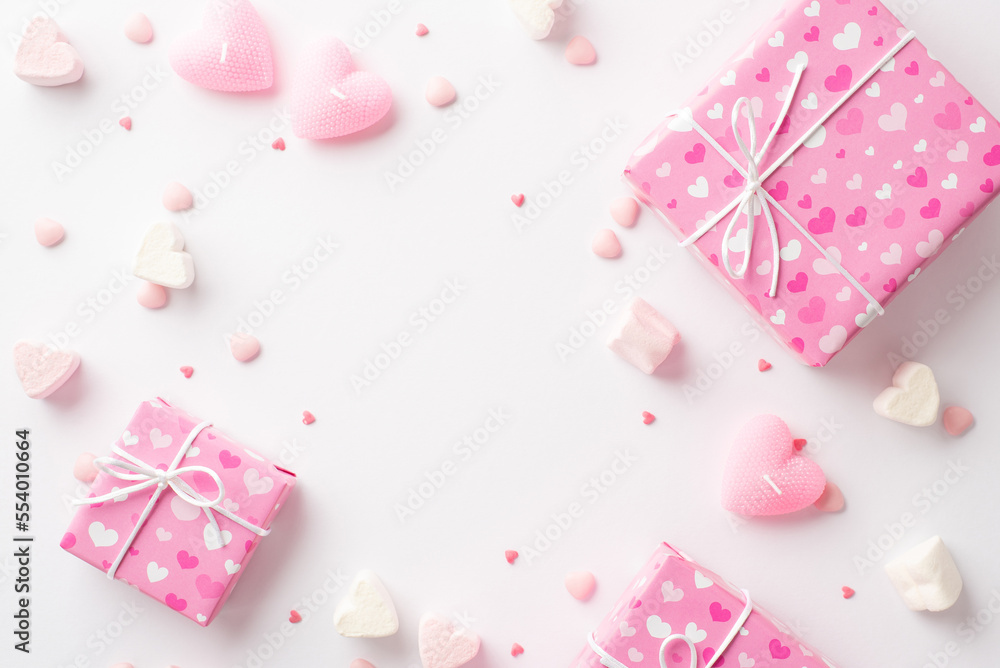 Valentine's Day concept. Top view photo of pink gift boxes heart shaped marshmallow candles and sprinkles on isolated white background with empty space in the middle Valentine's Day concept. Top view photo of pink gift boxes heart shaped marshmallow candles and sprinkles on isolated white background with empty space in the middle
