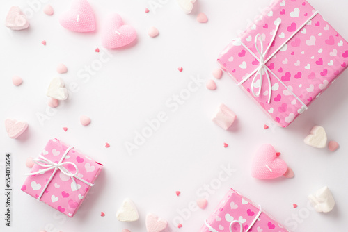 Valentine's Day concept. Top view photo of pink gift boxes heart shaped marshmallow candles and sprinkles on isolated white background with empty space in the middle