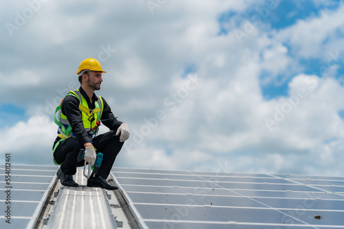 technician engineer working on checking maintenance service with solar batteries near solar panels at sunny day in solar power plant station on rooftop, electricity energy of photovoltaic industrial
